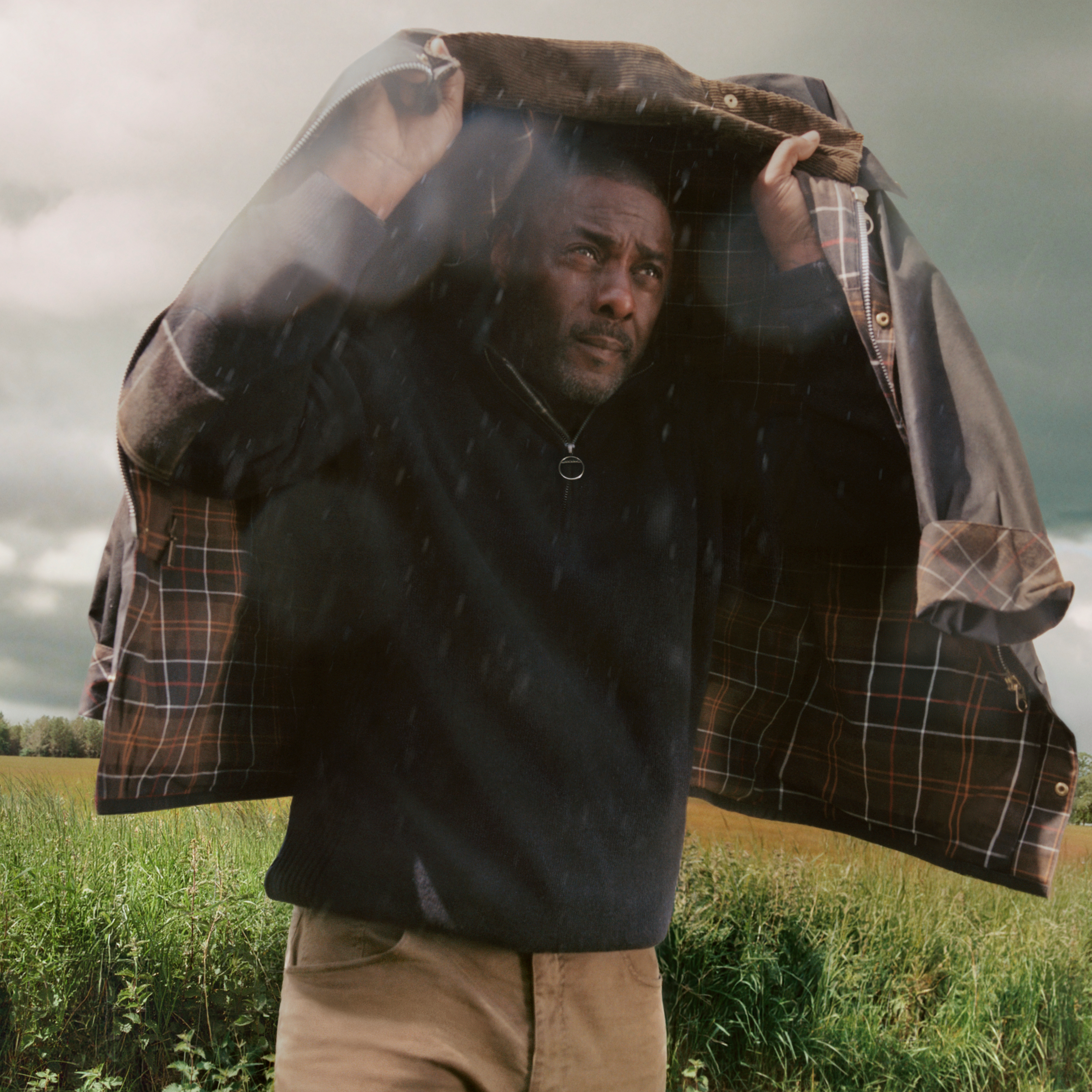 Sir Idris Elba with a Barbour waxed jacket over his head