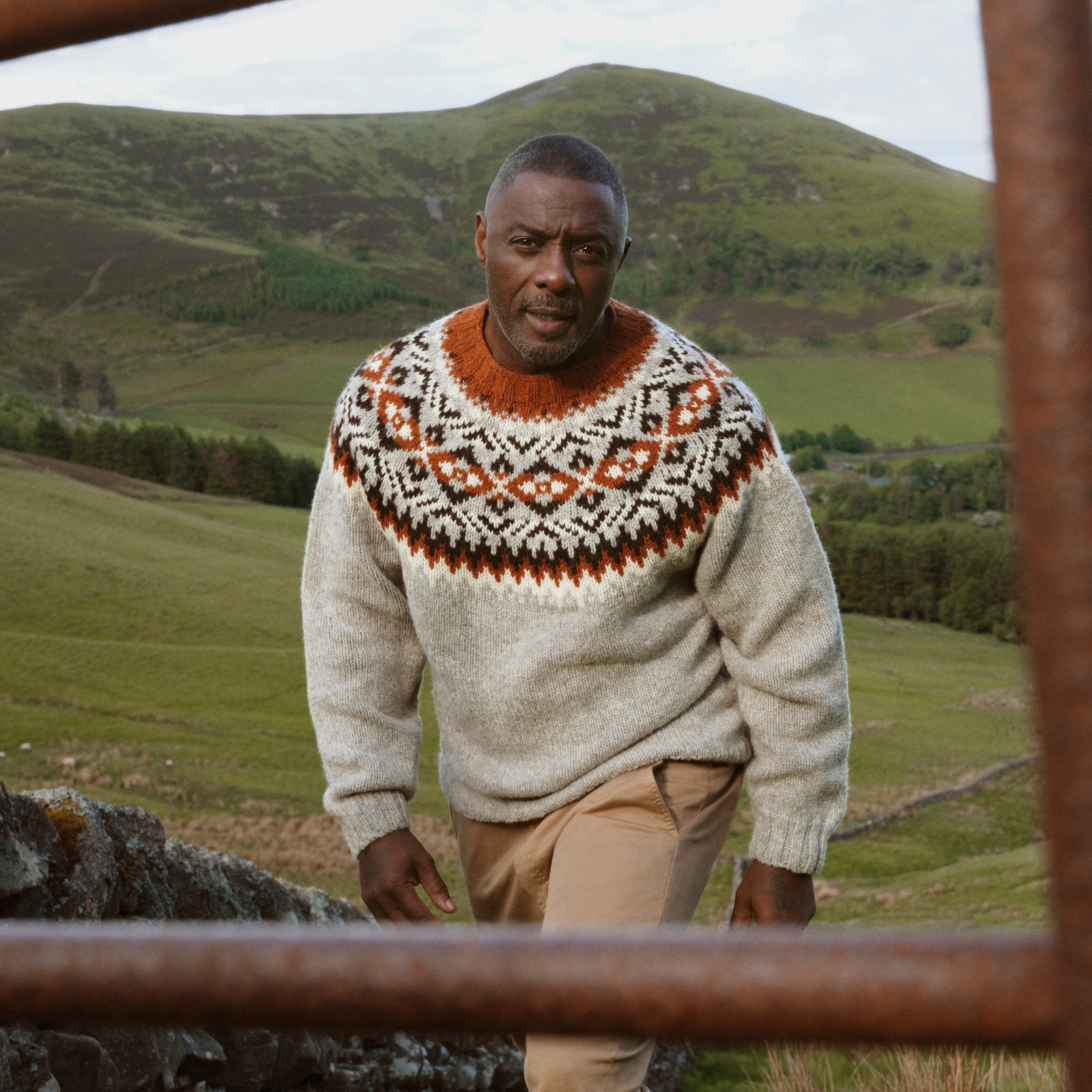 Sir Idris Elba with a Barbour knitted jumper on walking in a field